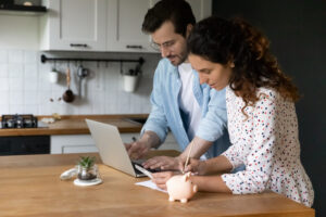Concentrated millennial spouses calculating family budget paying utility bills online using laptop. Busy married couple check review loan payments planning expenses choose effective way to save money
