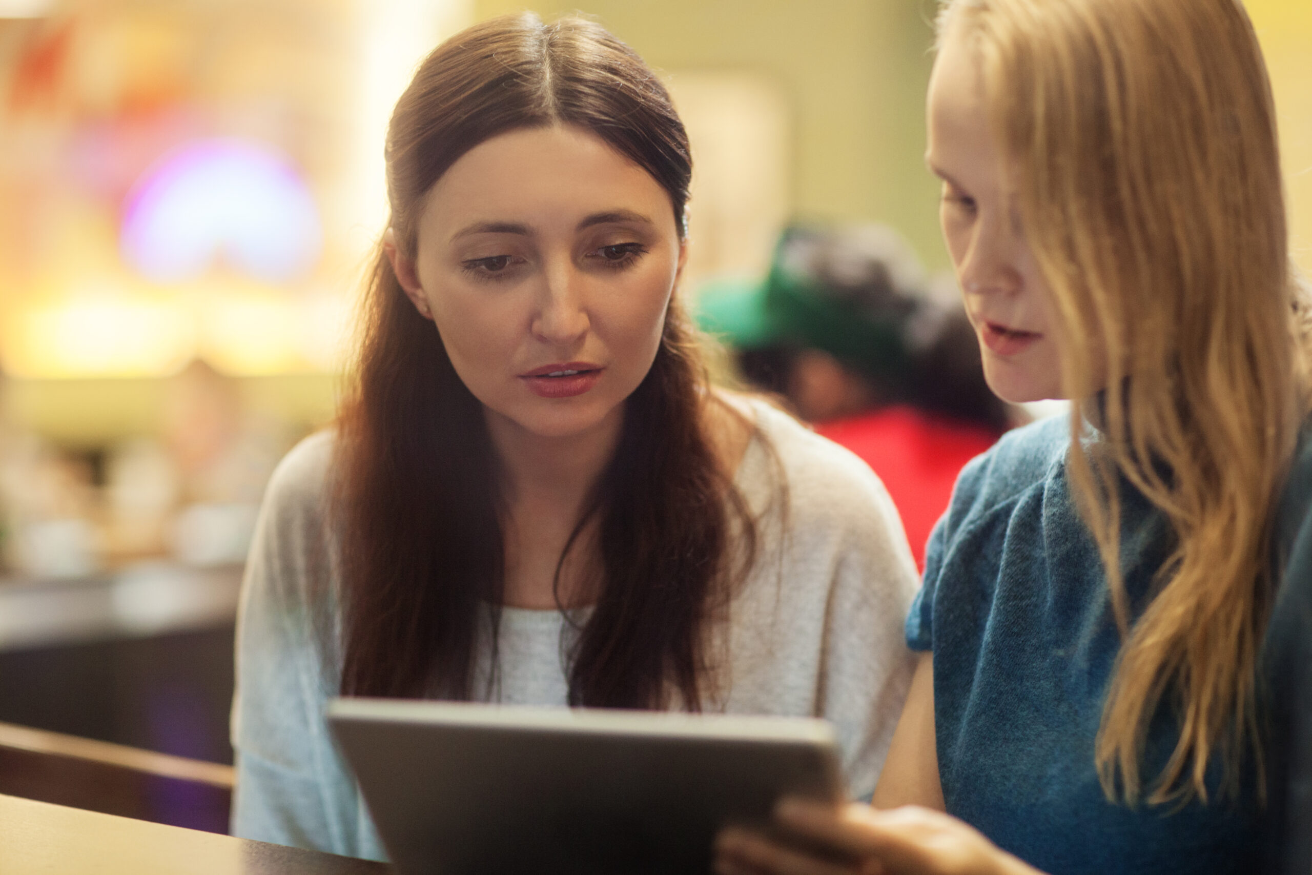Two women having a discussion in a restaurant viewing an electronic tablet | Web page on uterine polyps | CNJ | Wall Township
